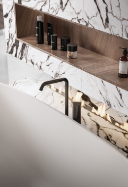 Ściana łazienkowa pokryta spiekiem San Simone o kremowo-beżowej bazie  z żyłkami w odcieniach szarości, brązu i złota.