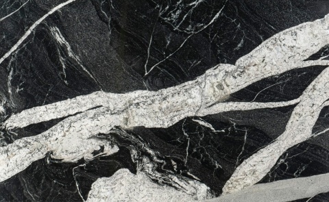 Naori to granit naturalny o ciemnym tle z kontrastującymi białymi i kremowymi żyłkami,