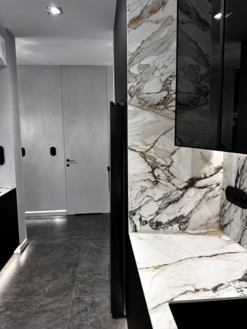 Blat roboczy i ściana wykończone spiekiem Calacatta Luxe o białym odcieniu i Ciepłym żyłkowaniu.