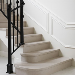 Schody wewnętrzne wykończone konglomeratem kwarcytowym SiQuartz Bologna z polerem, przy eleganckiej białej ścianie.