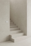 Nowoczesne schody wewnętrzne wykończone spiekiem Infinity Arkeon Fossil Matte w jasnoszarej, betonowej kolorystyce.
