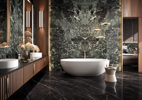 Łazienka z zielonym marmurem Verde France, wolnostojącą wanną i złotymi dodatkami oświetlenia.