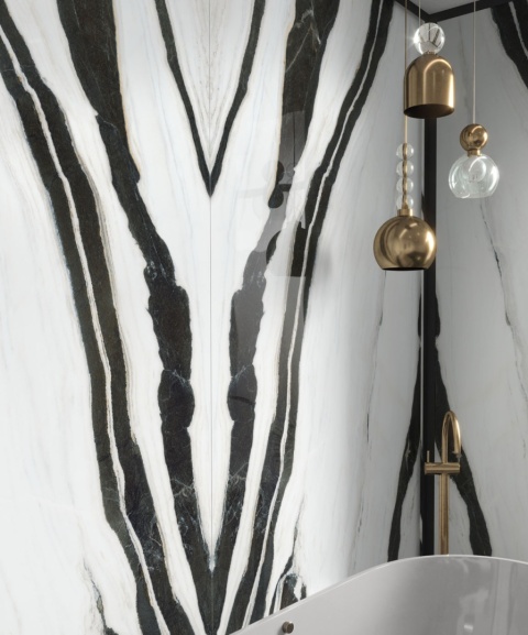 Detal ściany łazienki ze spiekiem Panda White w układzie bookmatch, w połączeniu ze złotą armaturą.