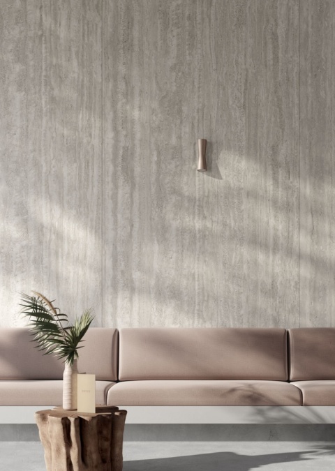 Ściana salonu wykończona spiekiem Travertino Chiaro z różowym zestawem wypoczynkowym.