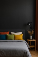 Nowoczesna sypialnia z ciemną ścianą Laminam Filo Pece, kontrastującą jasną pościelą i kolorowymi poduszkami.
