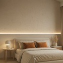 Sypialnia z dekoracyjną ścianą z konglomeratu Santamargherita Cotone, oświetlona ciepłym światłem wieczorem