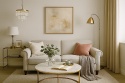 Salon glamour z sofą, spiekiem na ścianie, złotymi akcentami i naturalnym światłem podkreślającym tekstury.
