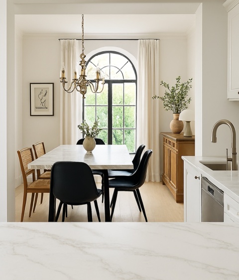 Widok z kuchni ze spiekiem Defense na jadalnię w stylu eklektycznym, marmurowy stół, złoty żyrandol i naturalne światło.