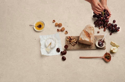 Blat Lumière matte z winogronami, pieczywem i serem – jasna powierzchnia idealna do kuchni.