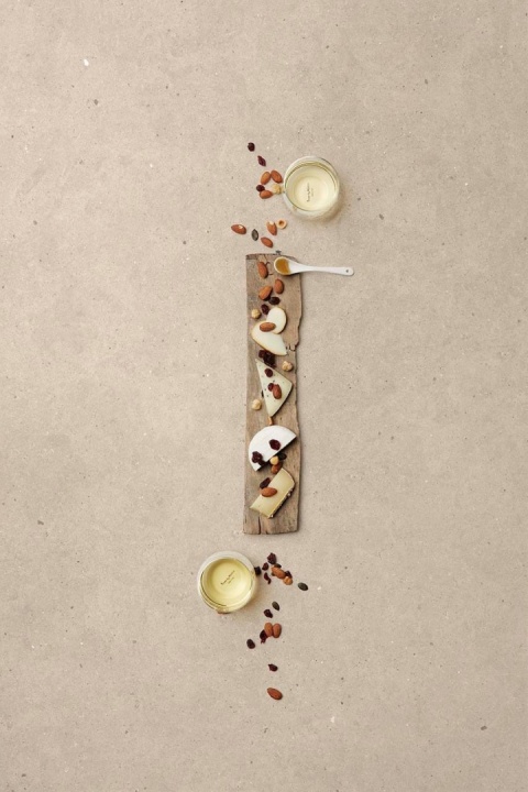 Jasny blat Lumière matte z serami, bakaliami i winem – eleganckie tło kulinarnych aranżacji.