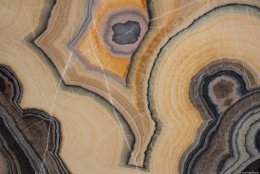 Zbliżenie kwarcytu Alexandrite – koncentryczne pierścienie w ciepłych odcieniach złota i brązu.