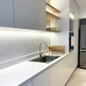 jasna kuchnia z białym blatem Silestone Blanco Zeus i ryflowanymi płytkami na ścianie.
