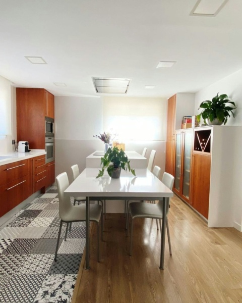 przestronna kuchnia z drewnianymi szafkami i białym stołem z blatem Silestone Blanco Zeus.