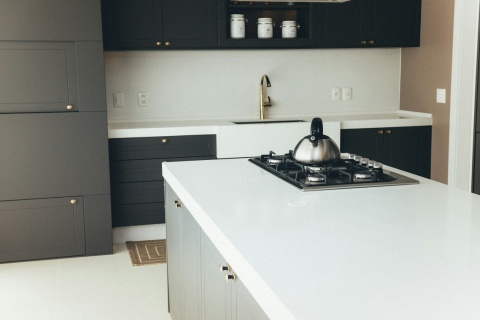 elegancka kuchnia z wyspą i białym blatem Silestone Blanco Zeus na tle ciemnych szafek.