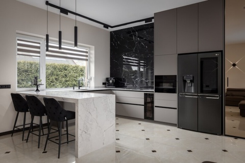 Nowoczesna kuchnia z wyspą w Silestone Eclectic Pearl i ścianą w kontrastowym czarnym spieku.