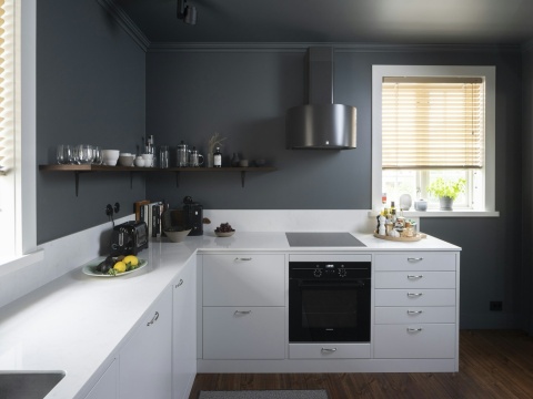 Nowoczesna kuchnia z białymi blatami Silestone Snowy Ibiza i ciemnymi ścianami kontrastującymi z wnętrzem