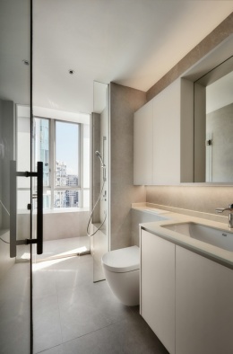 Łazienka w jasnych odcieniach szarości z kabiną prysznicową i blatami z materiału Dekton.