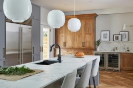 Nowoczesna kuchnia z dużą wyspą w Dekton Entzo, jasne wnętrze z drewnianymi akcentami.