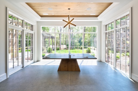 Elegancka jadalnia z dużymi przeszkleniami i podłogą w odcieniach grafitu.