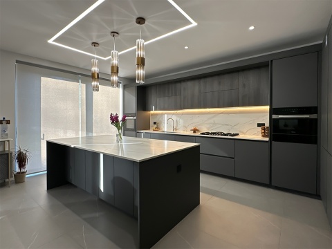 Nowoczesna kuchnia z wyspą i ścianą w tle wykończoną Dekton Morpheus