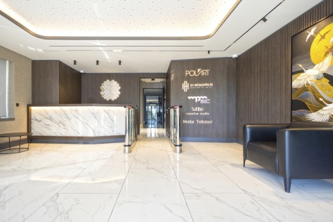 Elegancki hol biurowca z ladą recepcyjną i posadzką w Dekton Lucid o polerowanym wykończeniu X-Gloss.