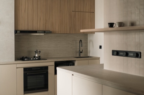 Kuchnia z blatem i ścianą w Dekton Marmorio Pietra Kode, w ciepłym, teksturowanym macie inspirowanym trawertynem.