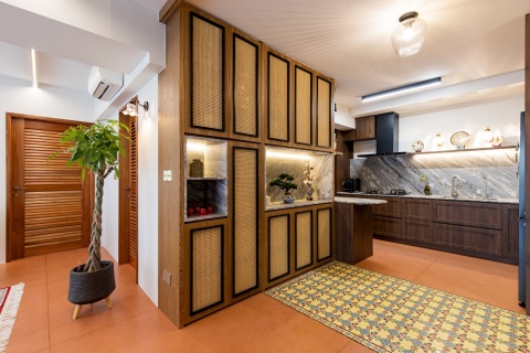 Kuchnia z drewnianymi szafkami i marmurowym blatem, z dekoracyjnymi frontami w stylu rattanowym.