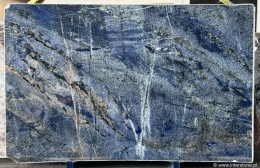 pełna płyta granitu Azul Bahia z widocznymi kontrastami barw: głębokim niebieskim tłem, bielą i ciemnymi akcentami mineralnymi.