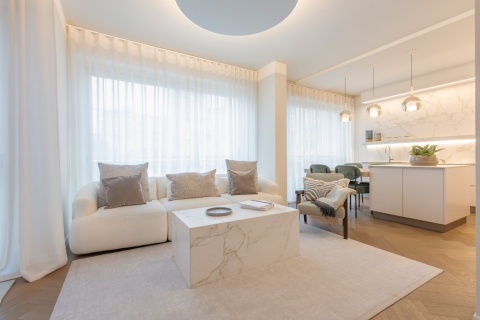 Nowoczesny salon z białym stolikiem kawowym wykonanym ze spieku Dekton Rem o wzorze marmuru.