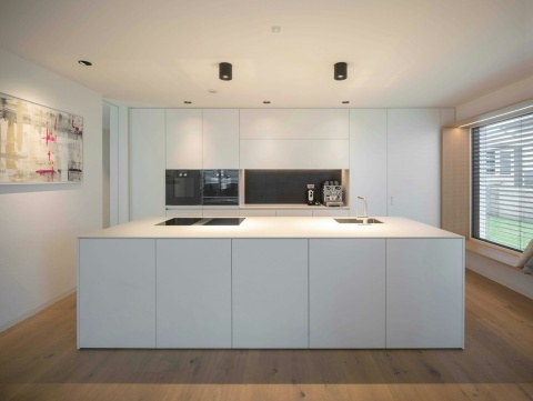 Minimalistyczna kuchnia z wyspą pokrytą Dekton Uyuni kC 20 mm w matowym wykończeniu.