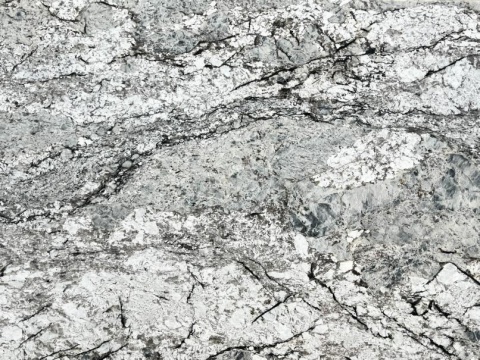 zbliżenie powierzchni kamienia, ukazujące kontrastowe przejścia barw i drobne akcenty brązu lub beżu na tle granitu.