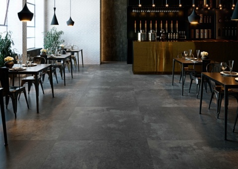 Restauracja z podłogą wykończoną spiekiem Grespania Moma Antracita Natural – eleganckie, industrialne wnętrze.