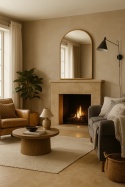 Salon eklektyczny z kominkiem wykończonym beżową płytą, miękkimi tekstyliami i naturalnym oświetleniem.