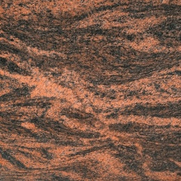 Zbliżenie granitu Multicolor Red o intensywnym czerwono-czarnym wzorze i charakterystycznym falistym użyleniu