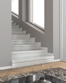 Schody wykończone cokołem z aglomarmuru Carrara o białej, subtelnie żyłkowanej powierzchni w nowoczesnym wnętrzu