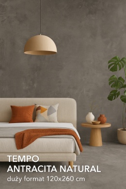 Salon z betonowym spiekiem Tempo Antracita Natural 120×260 cm, jasną sofą i zieloną monsterą w beżowej donicy.