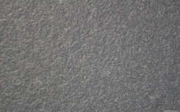 Zbliżenie faktury granitu Nero Zimbabwe szczotkowanego, chropowata ciemnoszara struktura kamienia