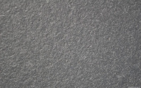 Zbliżenie faktury granitu Nero Zimbabwe szczotkowanego, chropowata ciemnoszara struktura kamienia