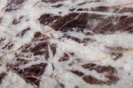 Zbliżenie kwarcytu Cherry ukazujące białe żyły na tle ciemnego burgundowego rysunku