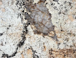 Fragment Patagonia z dużym kryształem kwarcu otoczonym kontrastowymi minerałam