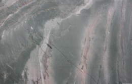 Zbliżenie struktury kwarcytu Tropical Green z falistymi żyłami i zieloną tonacją