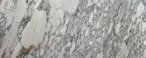 Zbliżenie marmuru Arabescato Vagli, białe tło z gęstym szaro-beżowym użyleniem o nieregularnym układzie.