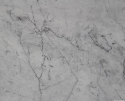 Zbliżenie marmuru Bianco Carrara C, jasnoszare tło z drobnym, nieregularnym szarym użyleniem.
