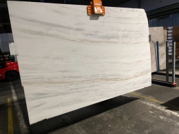 Płyta marmuru Bianco Lasa Covelano na uchwycie, jasne tło z delikatnymi szaro-beżowymi pasami