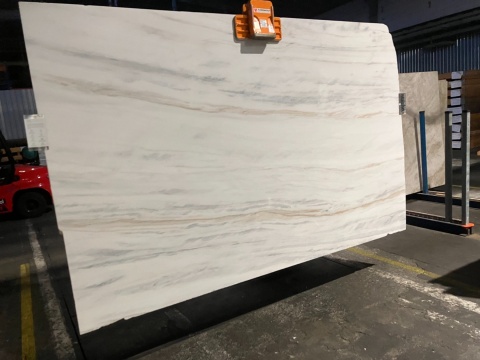 Płyta marmuru Bianco Lasa Covelano na uchwycie, jasne tło z delikatnymi szaro-beżowymi pasami