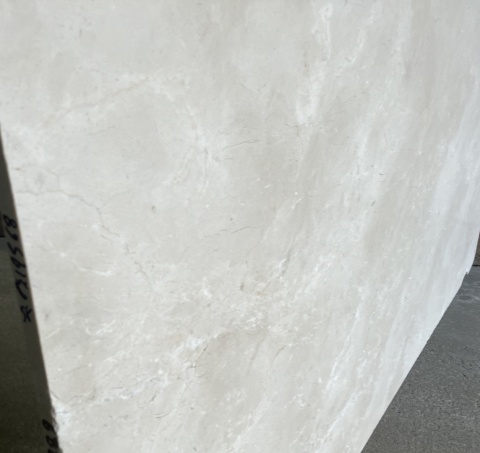 Zbliżenie krawędzi płyty marmuru Crema Marfil szlif, subtelny beżowy rysunek i matowe wykończenie