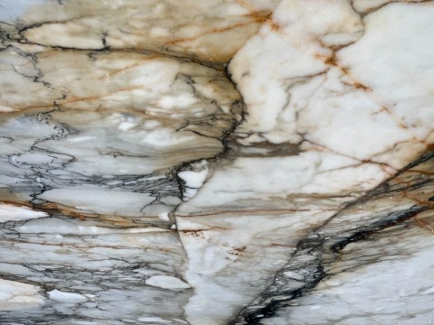 Zbliżenie marmuru Macchia Vecchia, jasne tło z nieregularnymi szarymi, złotymi i ciemnymi żyłkami o malarskim charakterze.