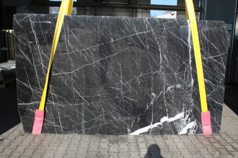 Płyta marmuru Nero Marquina, czarne tło z gęstą siecią cienkich białych żył, ustawiona pionowo.