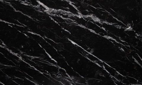 Fragment płyty Nero Marquina, czarne tło z ukośnymi białymi żyłami tworzącymi dynamiczny wzór.