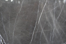 Zbliżenie marmuru Pietra Grey, jednolite szare tło z delikatną siatką jasnych, pionowych żył.